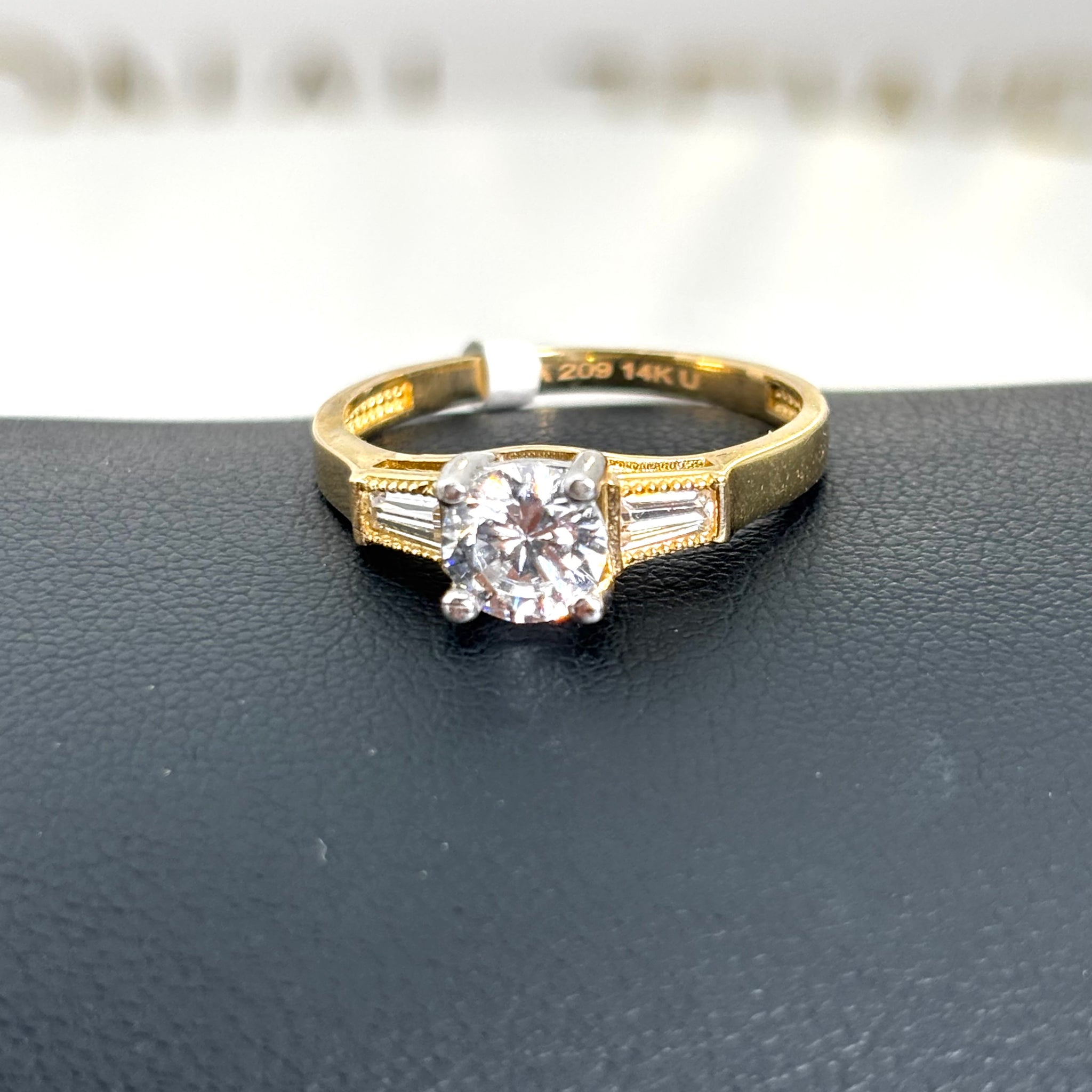 Anillo de compromiso con piedra circular y circonia baguette a los lados