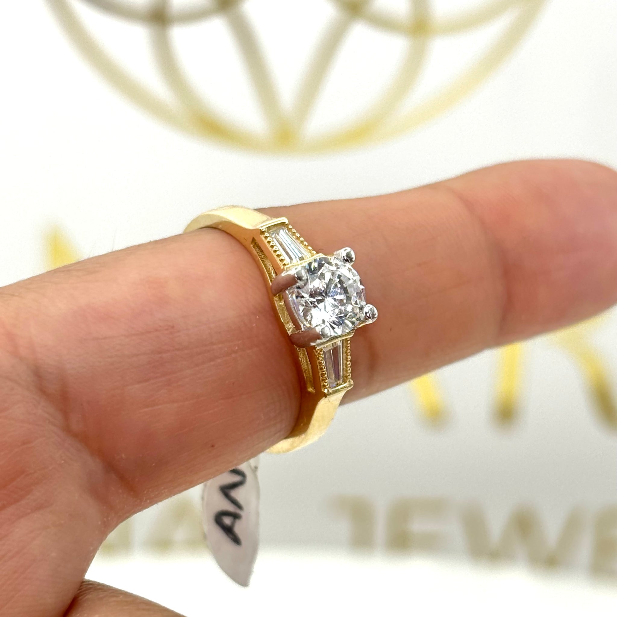 Anillo de compromiso con piedra circular y circonia baguette a los lados